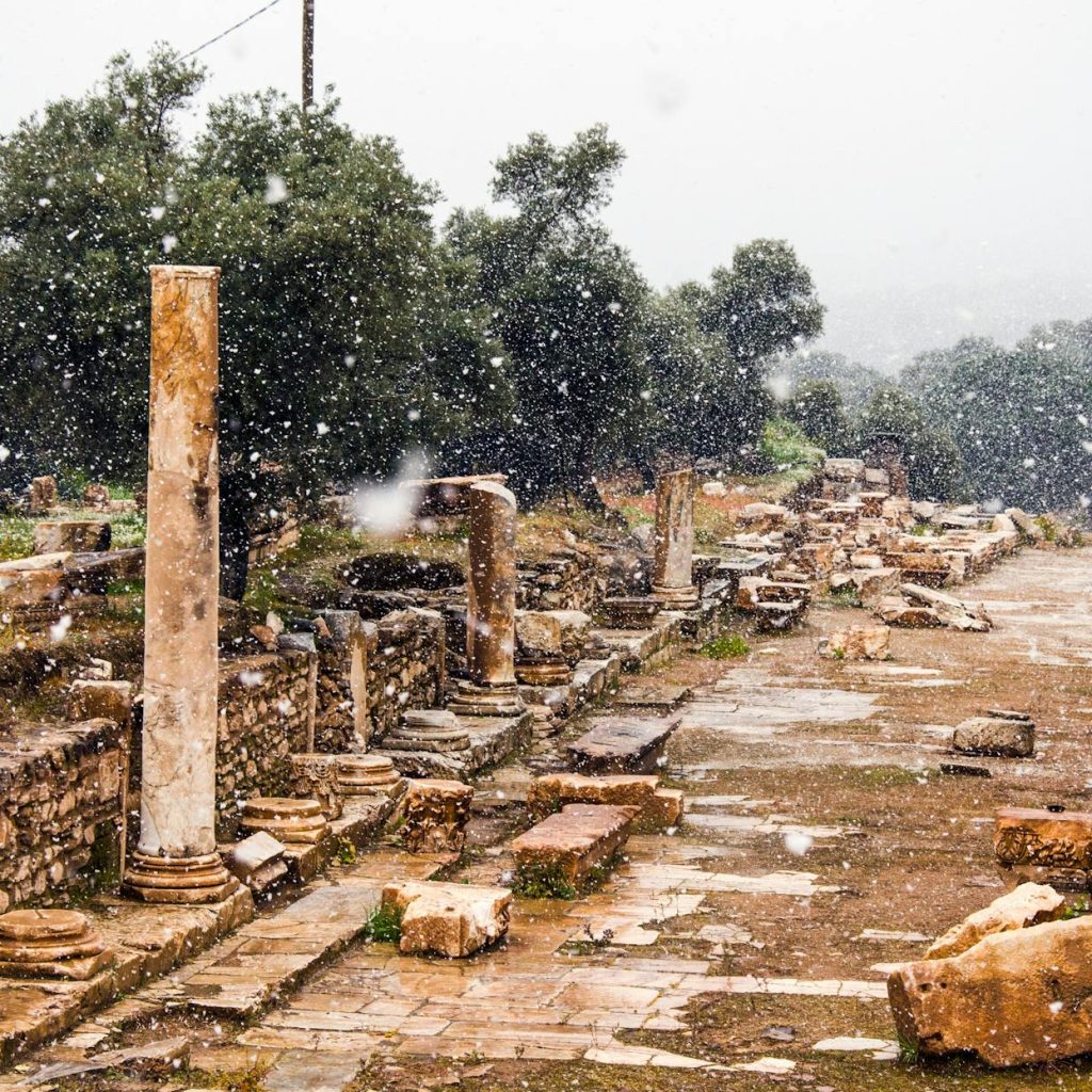 Snow falling on ancient ruins in Sultanhisar, Aydın, Turkey, creating a serene winter scene.