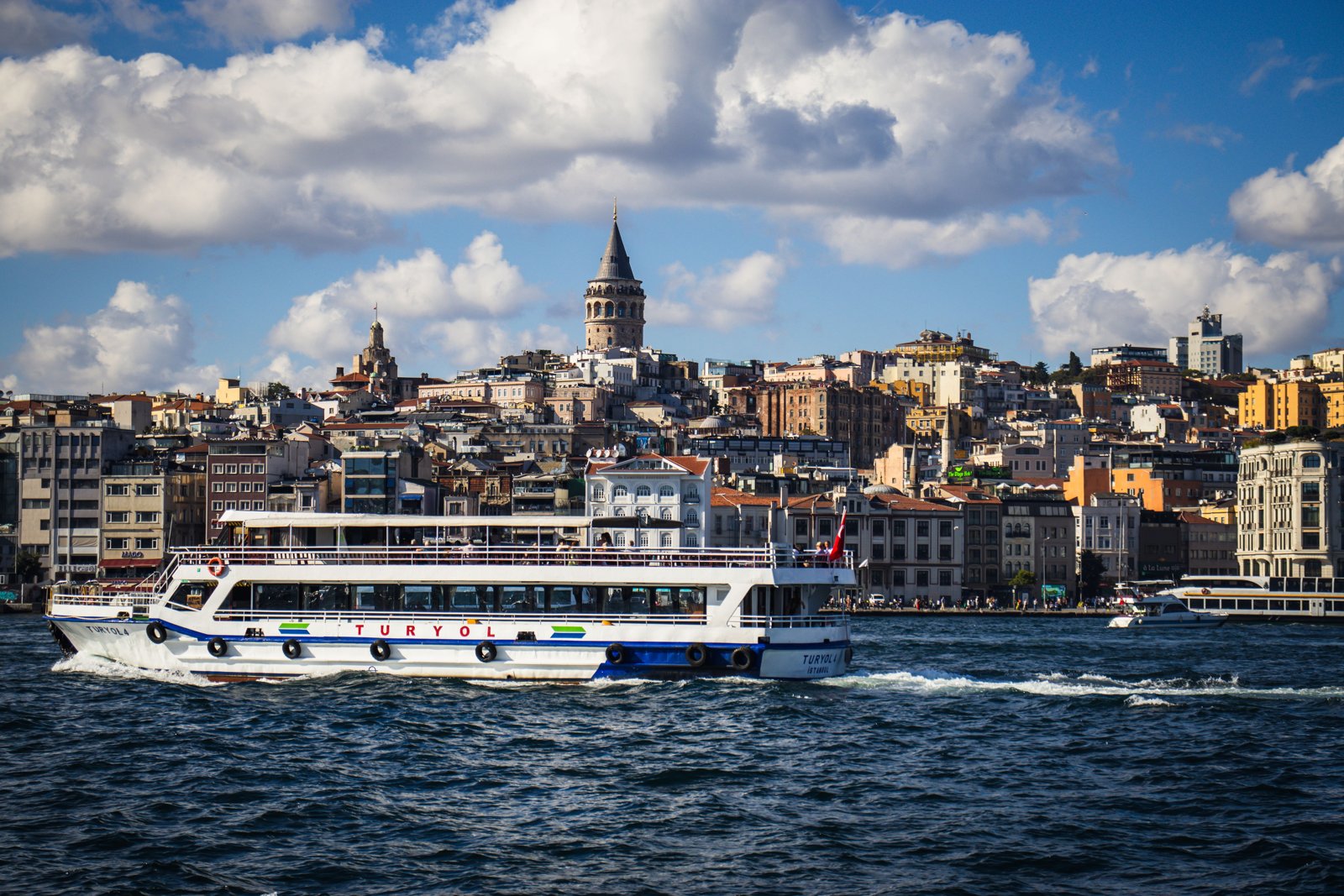 Scenic view of Istanbul's Galata Tower and a ferry on the Bosphorus under a bright sky