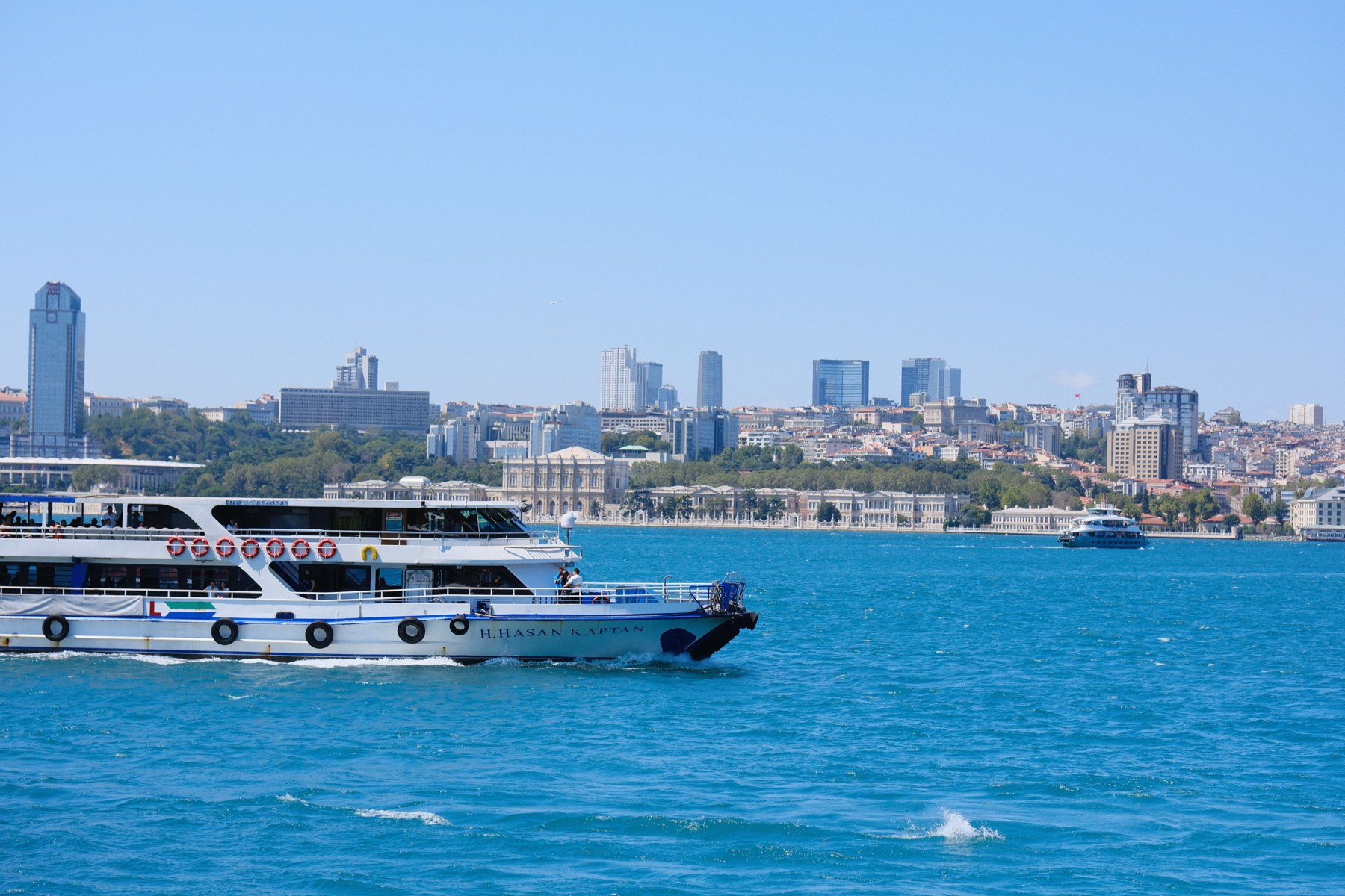 Cruise ships sail through the vibrant Bosphorus with Istanbul's skyline in the background, capturing a sunny day in Türkiye